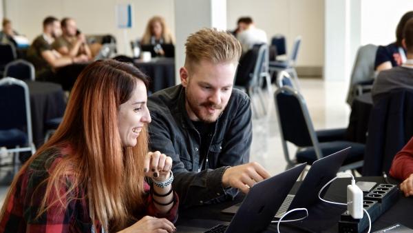 ckrina smiles while another contributor points at her laptop screen